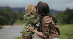 A mother gently kissing her young child outdoors, symbolizing the emotional tenderness explored in parenting guilt therapy.
