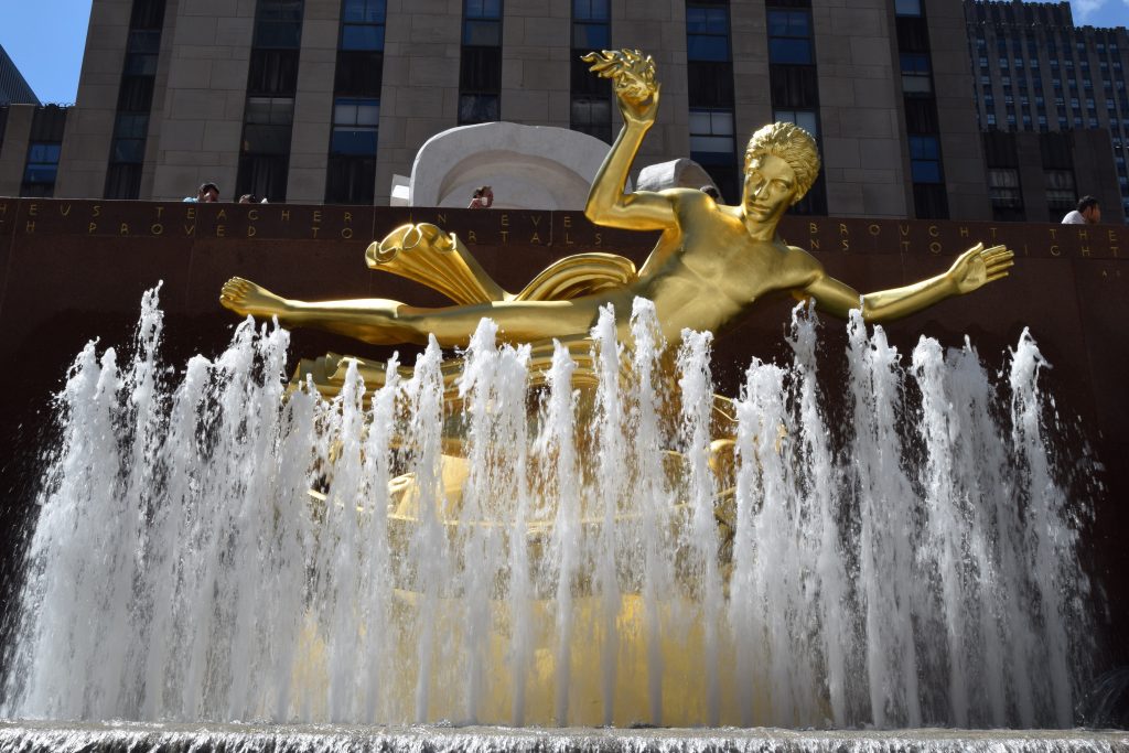 A golden statue of Prometheus soaring above cascading water, symbolizing the process of overcoming avoidance in therapy and igniting personal growth.
