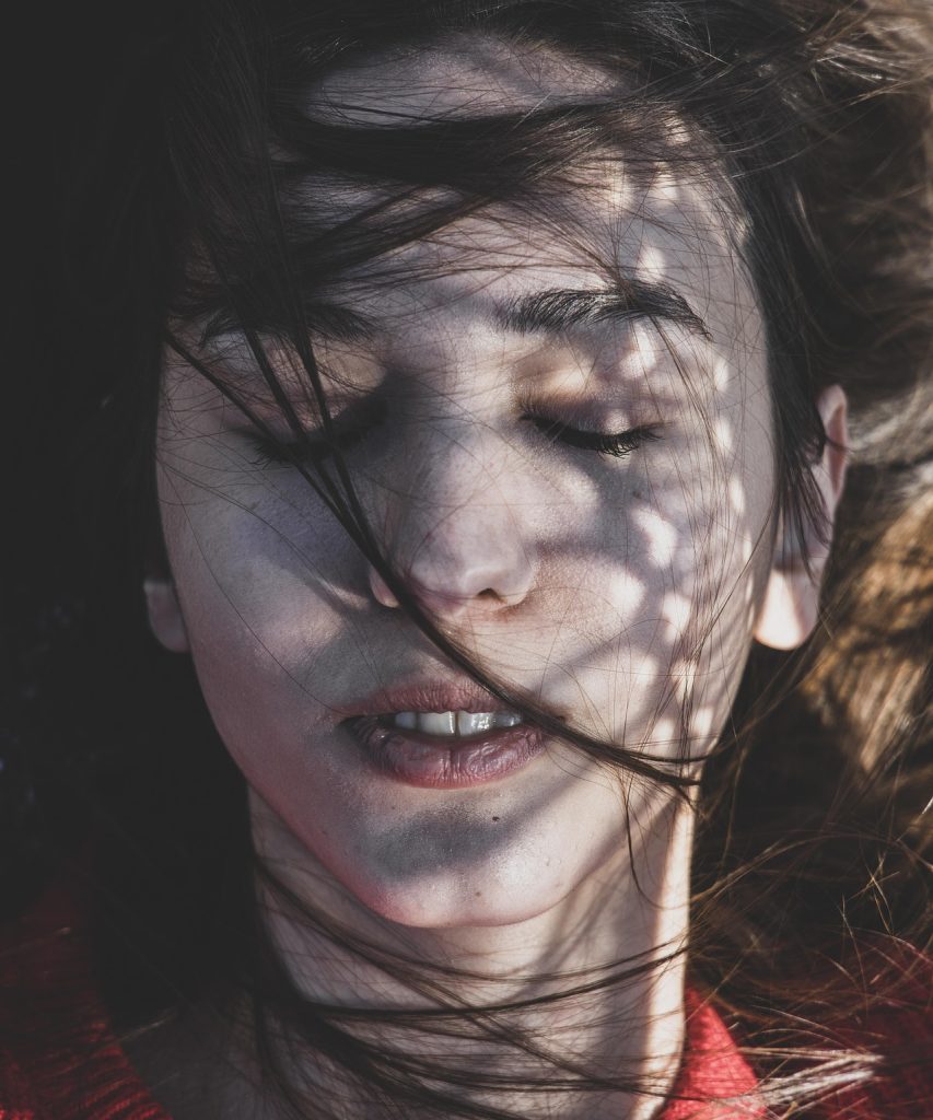 A teenage girl with eyes closed and hair gently blowing across her face, symbolizing the quiet emotional struggles addressed in virtual teen therapy in Ontario.