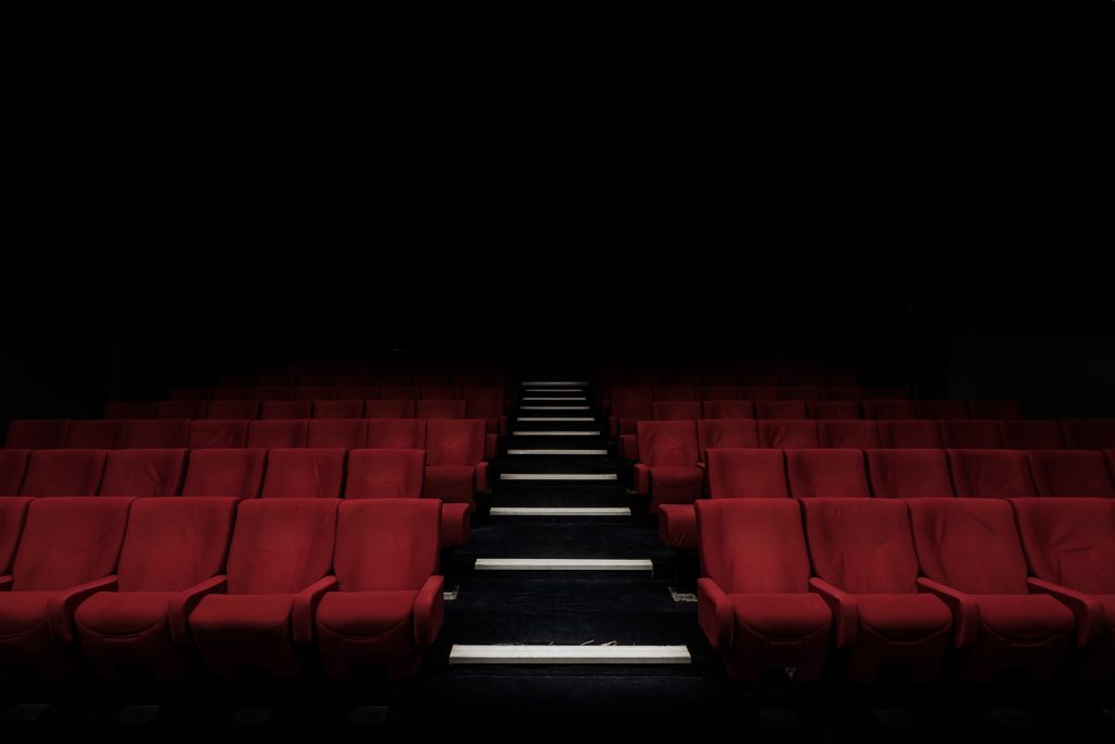 An empty cinema with red seats representing interpassivity and the challenge of how to stop compulsive scrolling.