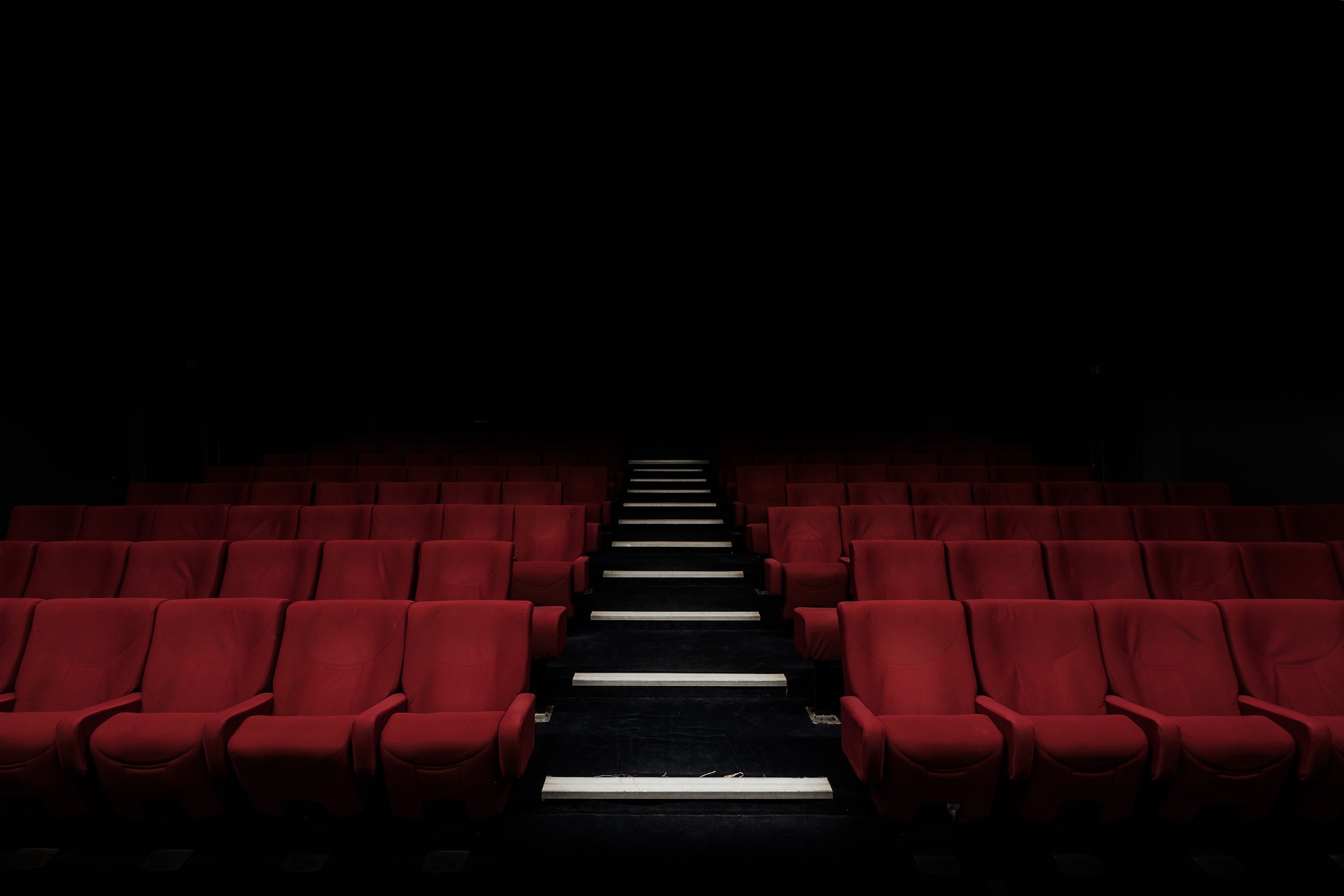An empty cinema with red seats representing interpassivity and the challenge of how to stop compulsive scrolling.
